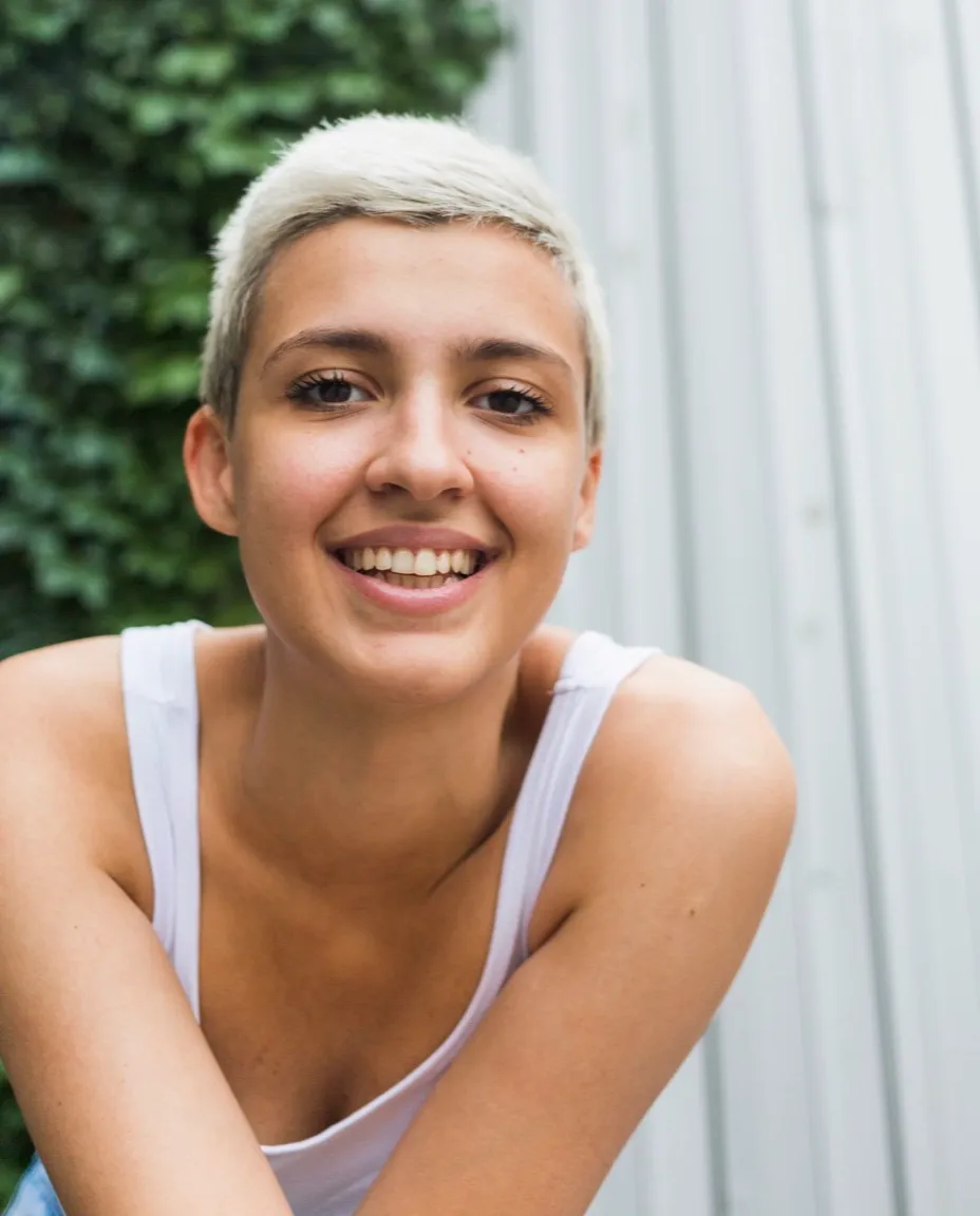 A smiling woman with short hair, outdoors in daylight